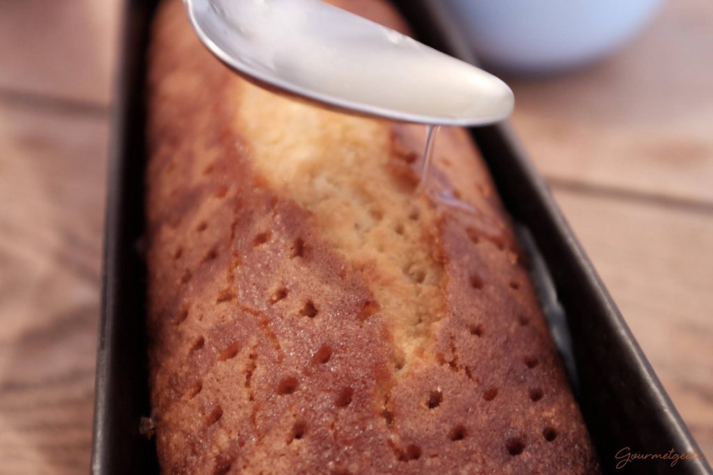 Mit einem Esslöffel das Zitronensaftgemisch über dem Kuchen verteilen.